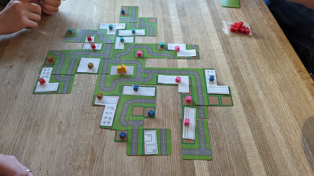 Overhead image of the game on a table. Multiple colors suggest four players are playing "We Built This City".